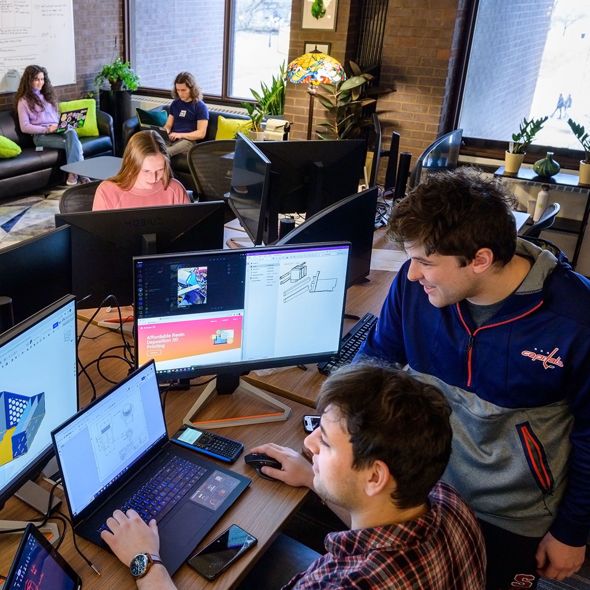 Two students collaborate on a computer while other two students work independently.