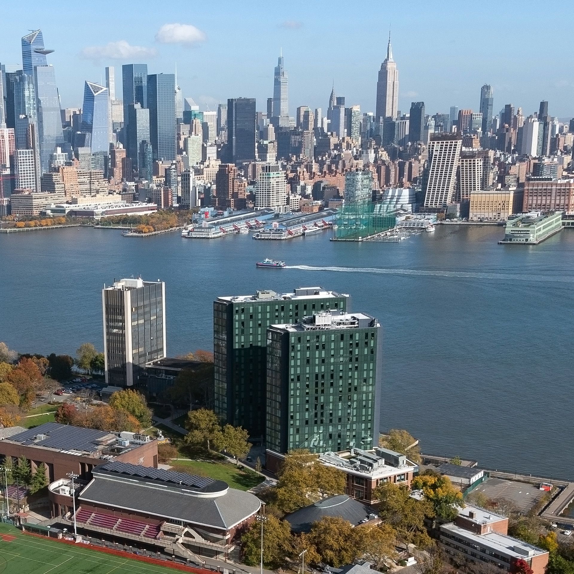 Aerial view of Stevens campus with Hudson River and Manhattan skyline beyond.