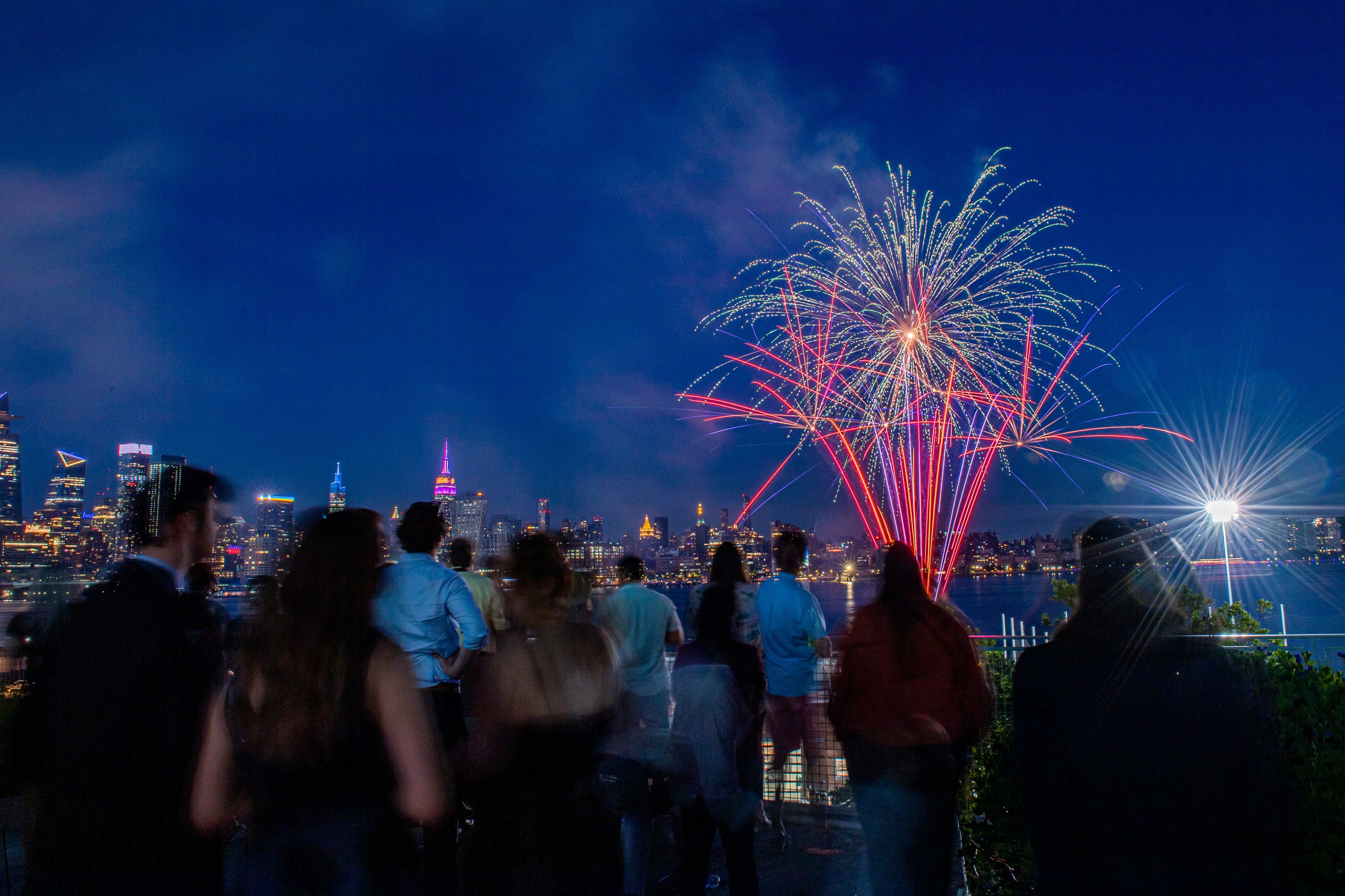 A crowd on Stevens campus watch fireworks with the New York skyline in background
