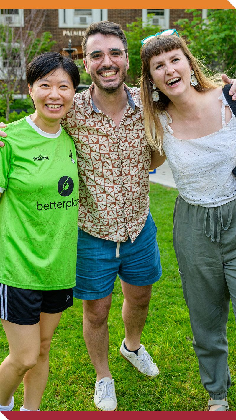 Three alumni laugh on campus.